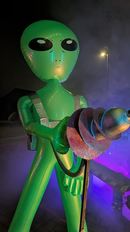 Low-angle view of the alien holding the blaster.