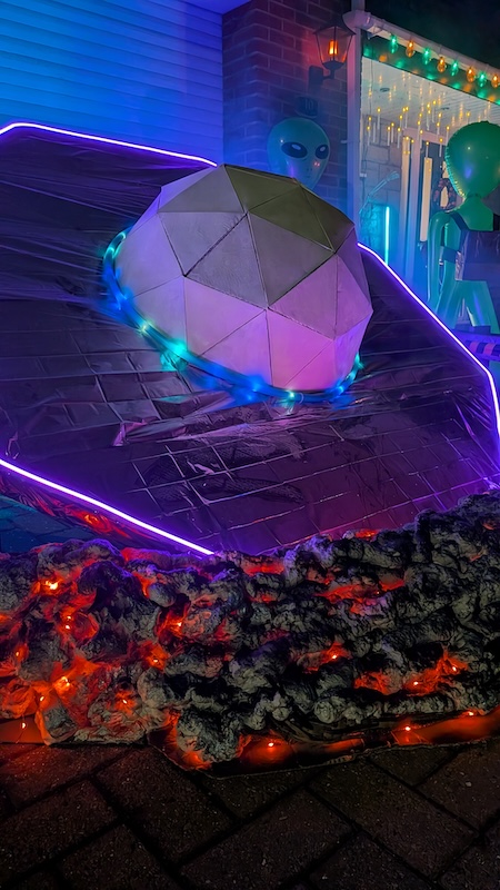 Low-angle view of the crashed UFO, focusing on the geodesic dome and the smouldering impact zone.